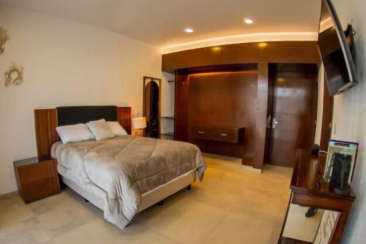Une chambre à coucher avec un lit, des tables de chevet, une télévision et une armoire.