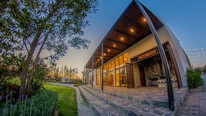A modern building with a sloped roof, large glass windows, and a stone pathway leading to the entrance. - Hotel Boutique Monte Penasco (Jilotepec)
