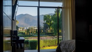 A bedroom with a large sliding glass door leading to a garden and mountains. - Hotel Boutique Monte Penasco (Jilotepec)