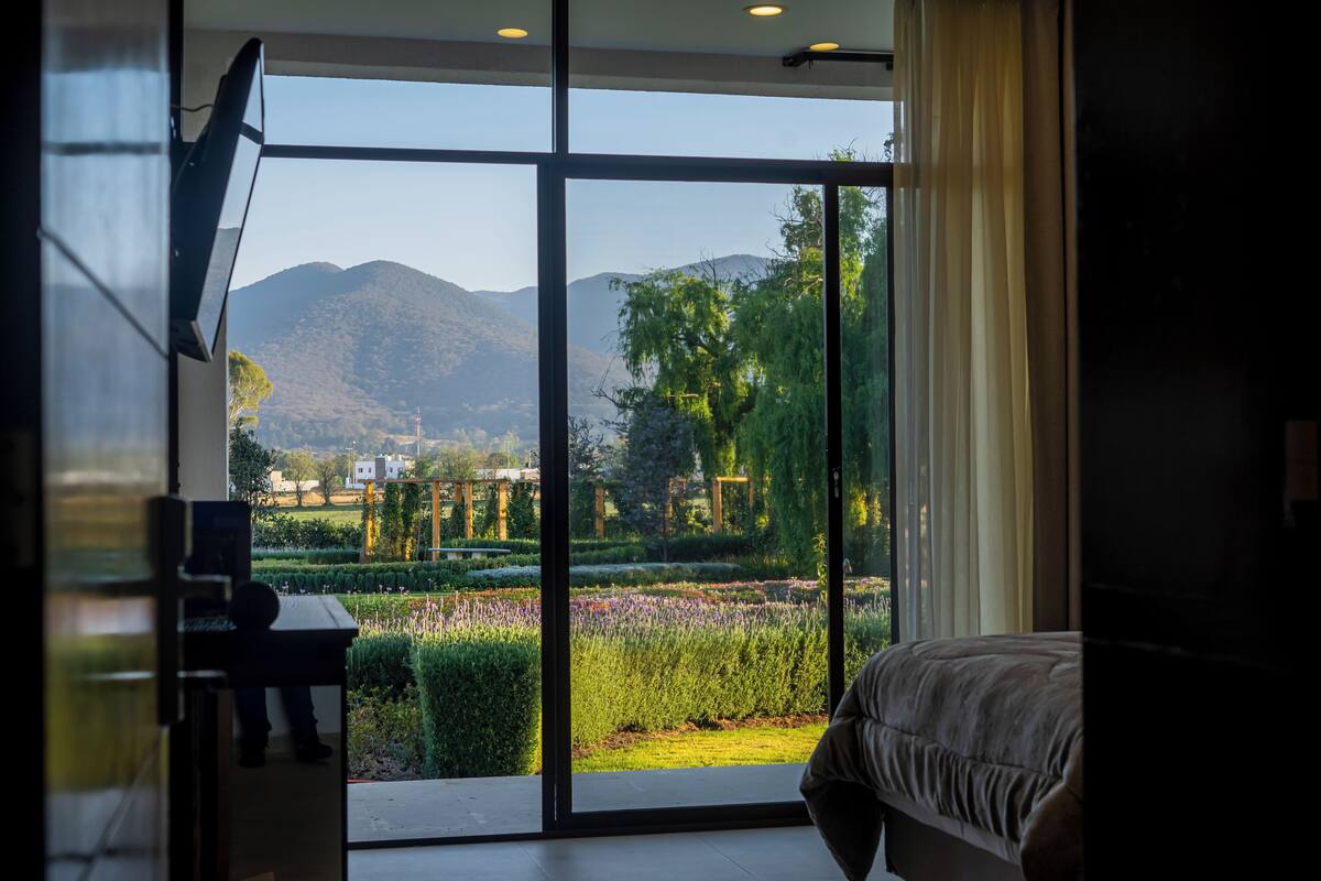 Une chambre dotée d’une grande porte-fenêtre coulissante donnant sur un jardin et des montagnes.