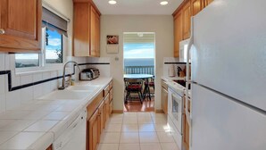 A kitchen with wooden cabinets, white countertops, a built-in oven, and a view to the outside.