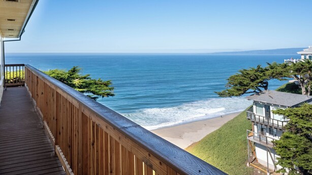 A wooden balcony overlooking a beach with ocean views.