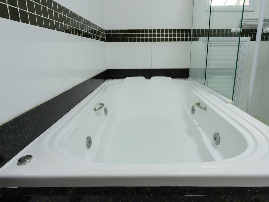 Un baño moderno con una bañera grande, cabina de ducha de vidrio y un salpicadero de azulejos blanco y negro.