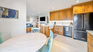 Une cuisine moderne avec des meubles en bois, un réfrigérateur en acier inoxydable et un coin repas comprenant une table ronde et des chaises.