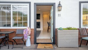 Une entrée moderne avec une porte en verre, un petit espace de repos à l’intérieur et un panneau portant le numéro 11 sur le mur.