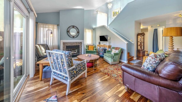 A spacious living room with a fireplace, a staircase, and a large window. - 8-Guest Marina Beach Home Near Monterey Bay (Marina)