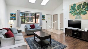 A modern living room with a sofa, a coffee table, a TV, and artwork on the walls. - La Selva Beach Retreat Near Manresa Beach (Watsonville)