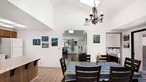 A modern kitchen with a built-in island, dining area with a table and chairs, and artwork on the walls. - La Selva Beach Retreat Near Manresa Beach (Watsonville)