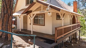 A wooden cabin with a number "42242" on the front, a porch, and a chimney. - Shaver Lake Cabin with Deck and Mountain Views (Auberry)