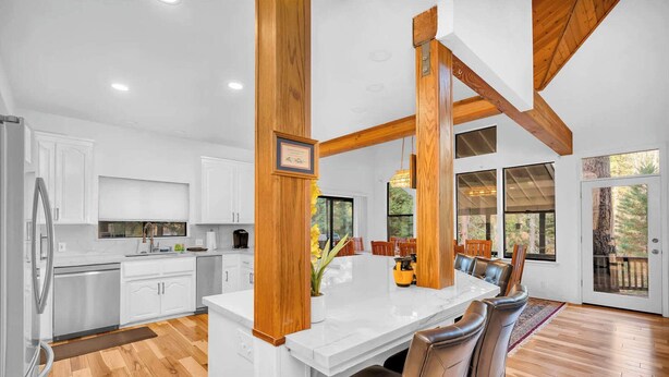 A modern kitchen with white cabinets, a large island, and wooden beams. - Creekside 3BR Near Yosemite South Gate Sleeps 8 (Fish Camp)