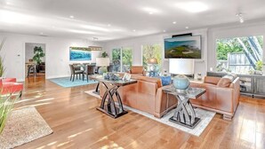 A spacious living room with a large TV, leather sofas, and a dining area with a table and chairs.