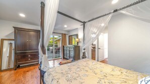 Quarto com uma cama de dossel, guarda-roupa de madeira e uma janela grande.