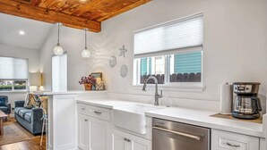 A modern kitchen with white cabinetry, a stainless steel dishwasher, and pendant lights. - Del Monte Beach Cottage Sleeps 4 with Private Yard (Seaside)