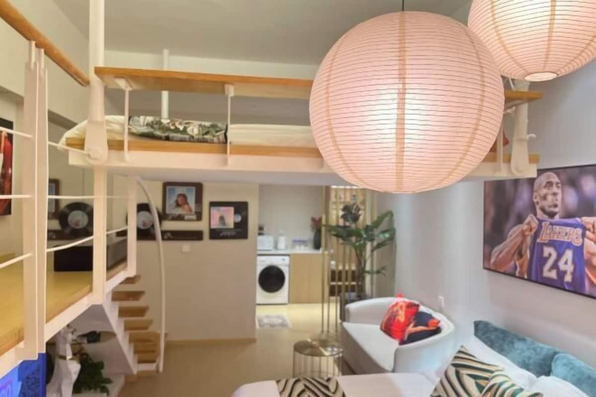 A modern interior with a bunk bed, a dining area, and a kitchen in the background.