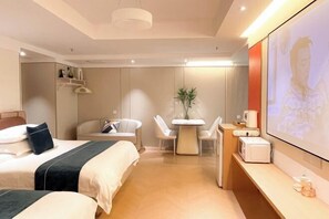 Una camera d'albergo moderna con due letti, un tavolo da pranzo, una TV e un forno a microonde.