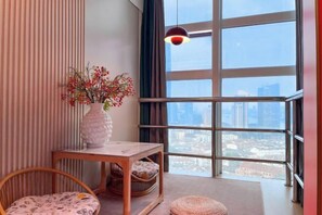 Une chambre moderne dotée d’une grande fenêtre, d’une table en bois, d’une chaise en osier et d’un vase décoratif.
