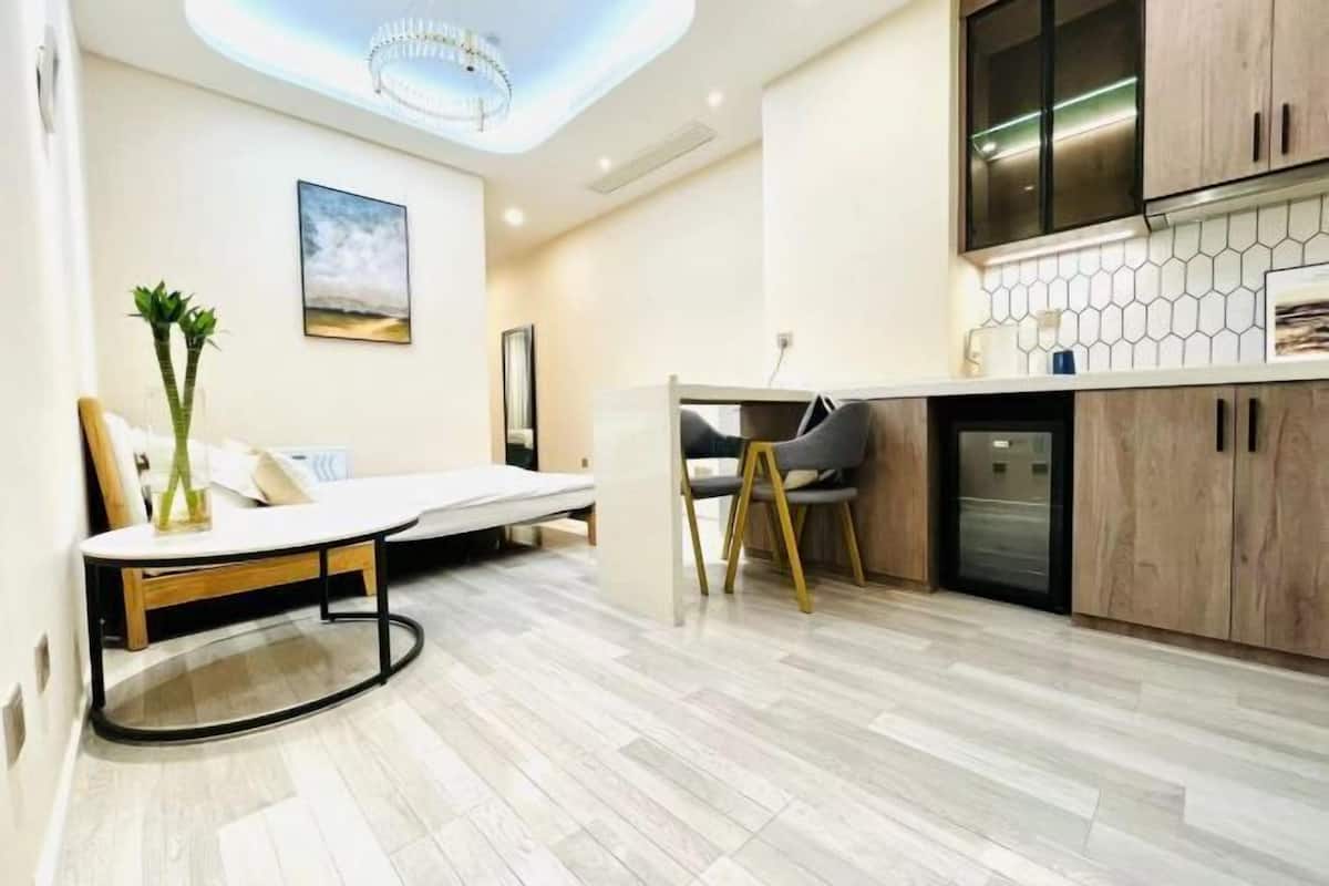 A modern kitchen with a dining area, a sofa, and a ceiling light fixture.