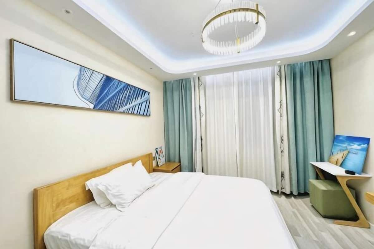 A hotel room with a large bed, a desk, a TV, and a painting on the wall.