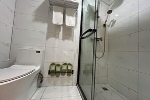 Ein Badezimmer mit Toilette, einer gläsernen Dusche und einem Handtuchhalter mit mehreren Handtüchern.