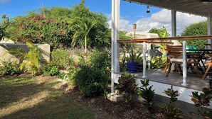 A covered outdoor seating area with chairs and tables, surrounded by lush greenery and flowering plants. - Villa By The Bay
Luxury 3 bedroom all ensuite, private pool, pickleball court (Bridgetown)