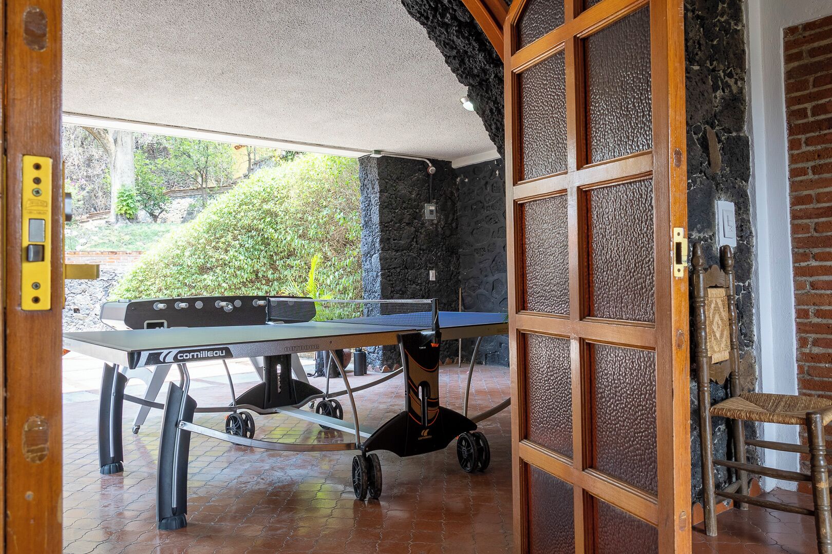 A ping pong table in a room with a stone wall and a wooden door.