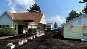 Un motel doté d’une entrée abritée, d’une allée en gravier et de jardinières fleuries.