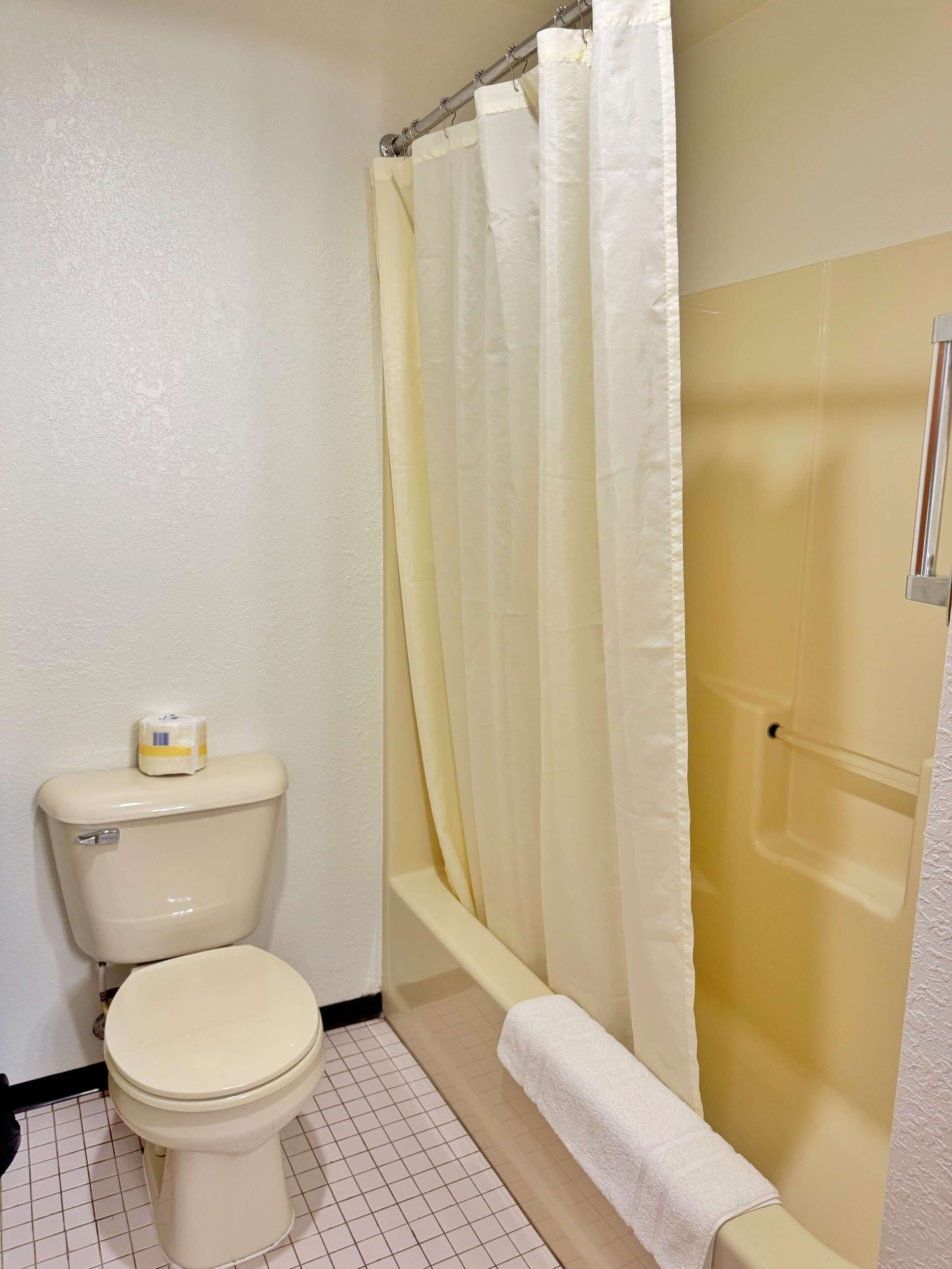 Un baño con inodoro, bañera y cortina de ducha.