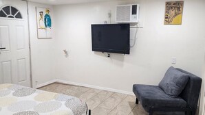 Une pièce comprenant un lit, un téléviseur fixé au mur, un canapé et une petite table.