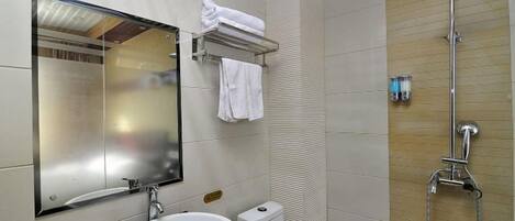 A bathroom with a sink, mirror, toilet, and shower.