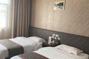 Habitación de hotel con dos camas, una mesita de noche, un cuadro en la pared y una ventana con cortinas.