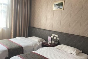 Habitación de hotel con dos camas, una mesita de noche, un cuadro en la pared y una ventana con cortinas.