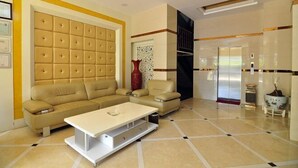 A modern living room with a beige sectional sofa, a white coffee table, and a red vase. - Luoping Star River Express Hotel (Luoping)