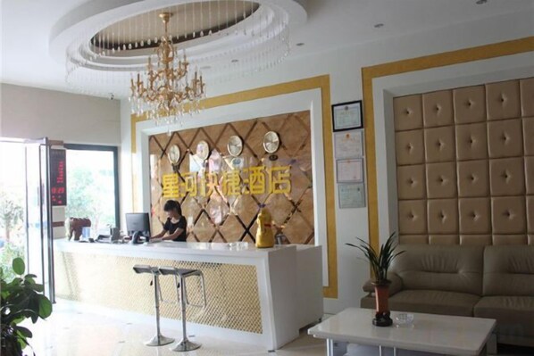A hotel reception area with a reception desk, a chandelier, a sofa, and a potted plant. - Luoping Star River Express Hotel (Luoping)