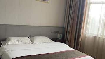 Ein Hotelzimmer mit einem Bett, einem Nachttisch, einem Telefon und einem Fenster mit Vorhängen.