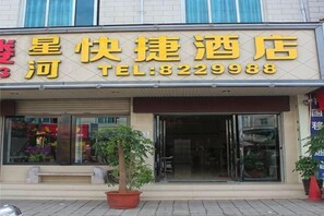 Ein Hotel mit gut lesbarem Schild, einer Telefonnummer und einem Blumentopf vor der Fassade.