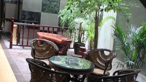 A patio with wicker furniture, a glass table, and potted plants. - Luoping Star River Express Hotel (Luoping)
