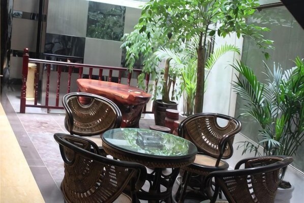 A patio with wicker furniture, a glass table, and potted plants. - Luoping Star River Express Hotel (Luoping)