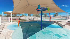 A water play area with a pool, a shaded canopy, and a fenced perimeter.