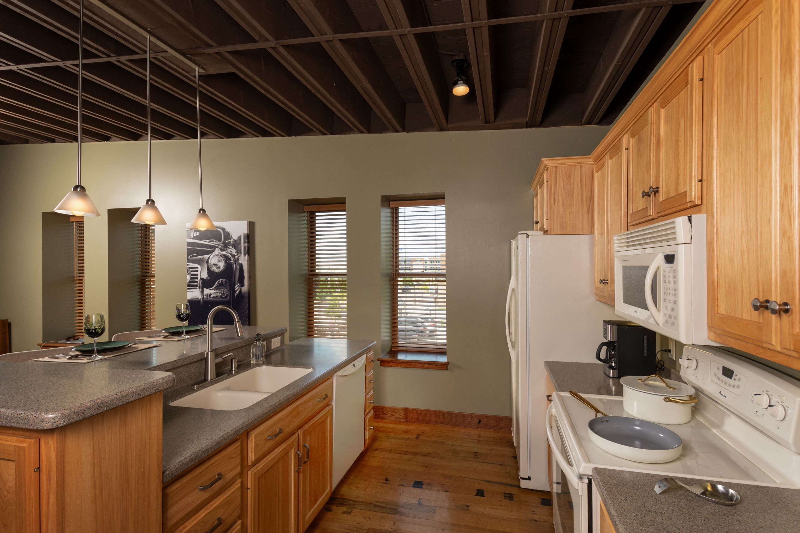 A kitchen with wooden cabinets, a granite countertop, a sink, a stove, and a microwave.