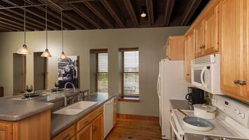 A kitchen with wooden cabinets, a granite countertop, a sink, a stove, and a microwave.