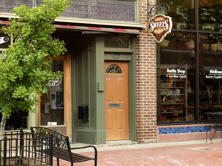 A storefront with a green door, a bench outside, and a sign for 'Sweets on Bed'.