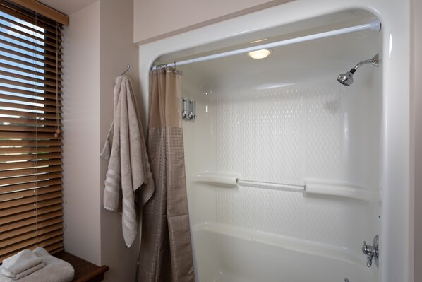 A bathroom with a bathtub, a towel rack with towels, and a window with blinds. - 3rd Street Lofts (Wausau)