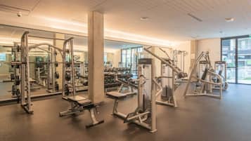 Ein Fitnessstudio mit verschiedenen Trainingsgeräten, großen Fenstern und einem aufgeräumten, modernen Design.