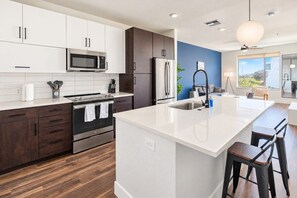 A modern kitchen with a central island, stainless steel appliances, and a view to the outdoors. - Heart of Tempe 1BD with Pool, Gym, Parking (Tempe)