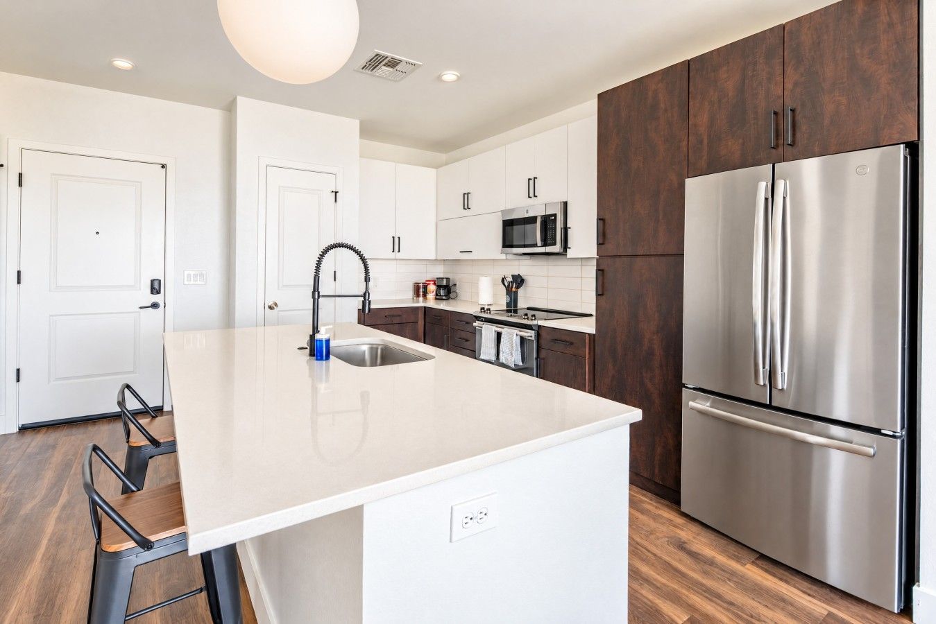 A modern kitchen with a central island, stainless steel appliances, and a wooden accent wall.