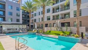 Un hôtel moderne doté d’une piscine, de palmiers et d’un immeuble à plusieurs étages avec des balcons.