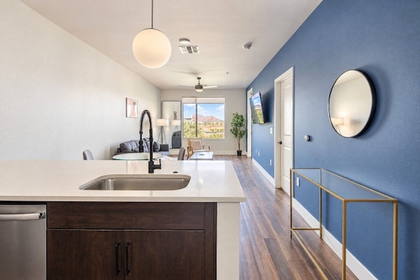 A modern kitchen with a large island, a dining area, and a view of the outdoors.
