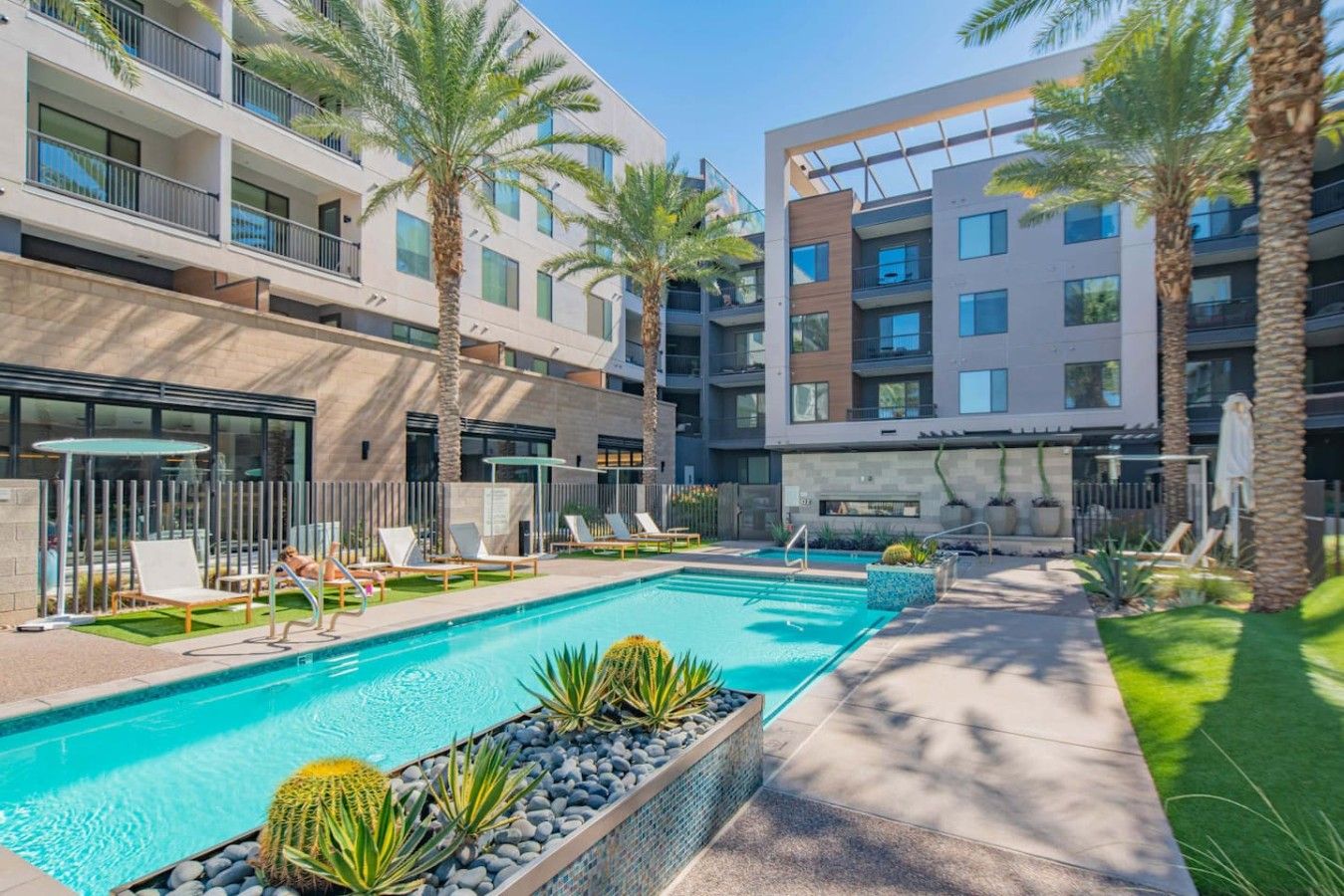 Un hôtel moderne doté d’une piscine, de chaises longues et de palmiers.