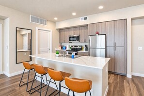 A modern kitchen with a central island, stainless steel appliances, and wooden cabinets.