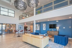 A spacious lobby with a high ceiling, a seating area with a sofa and chairs, a bar area, and artwork on the walls. - DT Tempe Retreat | Pool,Gym,Parking,W/D,Balcony (Tempe)